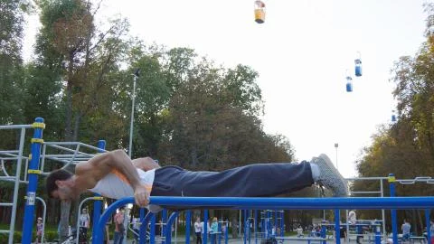 Athletic man doing push ups on parallel bars at sports ground in city park 写真素材
