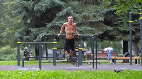 Athletic man doing pushups on bars in City Park. Workout Stock-Footage 66420671