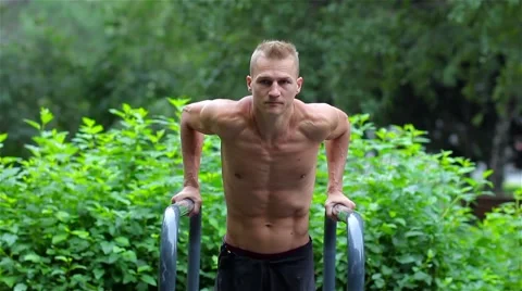 Athletic man doing pushups on bars in City Park. Workout. Closeup Stock Footage 66420685