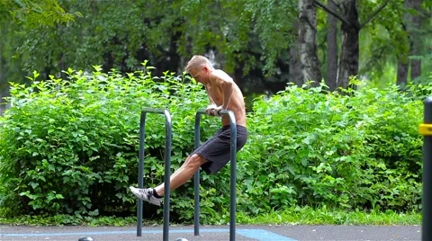 Athletic man doing pushups on bars in City Park. side view. Workout Stock-Footage 66420698