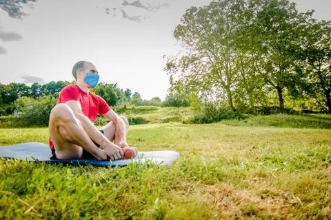 Athletic man doing stretching in nature with virus mask Stock Photos