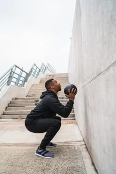 Athletic man doing wall ball exercise. Stock Photos