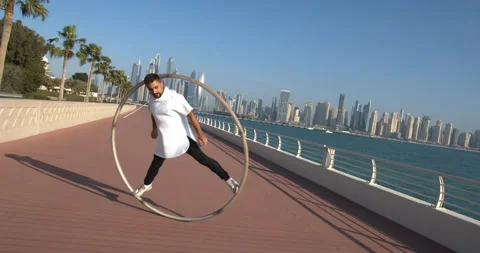 Athletic man is doing wheel gymnastics on The Palm Jumeirah, Dubai, UAE, 4k Stock Footage 151683715
