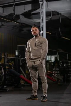 Athletic man dressed in fitted training outfit stands triumphantly in Stock Photos