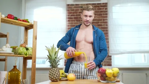 Athletic man drinking fruit juice from a glass in the kitchen at home. Attractiv Stock Footage 143752911