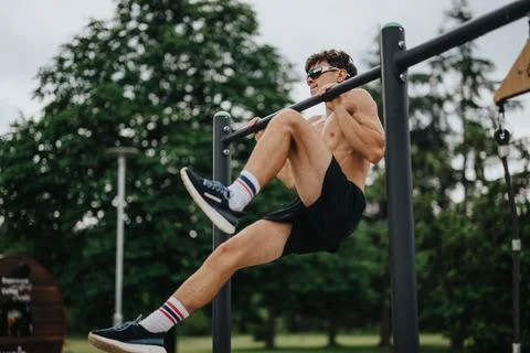 Athletic man exercising on parallel bars outdoors in the park Stock-Fotos