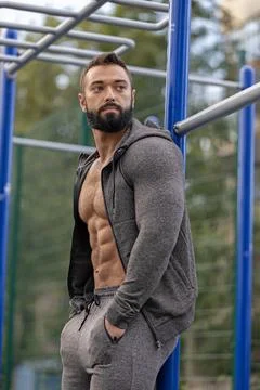 Athletic man in gray outfit posing on sports ground during daytime exercise Stock Photos
