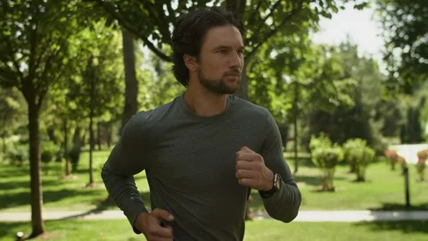 Athletic Man, a guy jogging in the park on a background of trees, Close-up Video stock 115407147