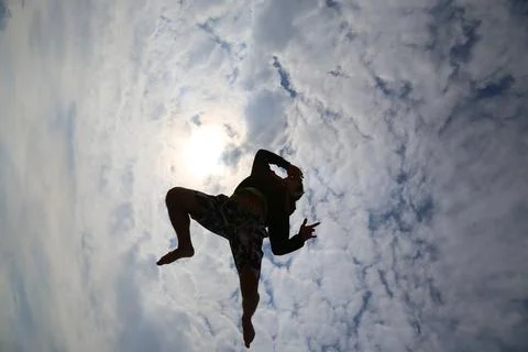 Athletic man handstand pose on beach, upside down silhouette, sky background Stock Photos