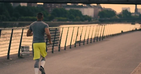 Athletic man jogging along the riverside listening to music in Frankfurt am Main Stock Footage 85489210
