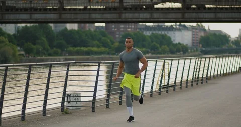 Athletic man jogging along the riverside listening to music in Frankfurt am Main Video stock 85510999