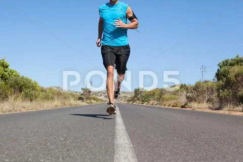 Athletic man jogging on open road Stock Photos
