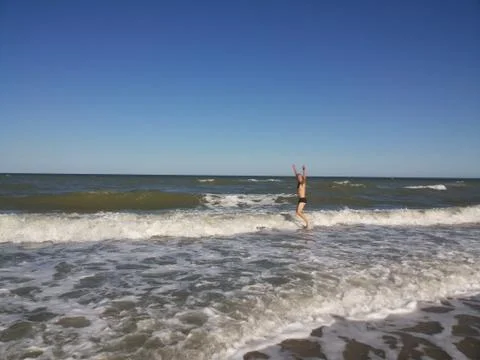 Athletic man jumping through waves Stock Photos