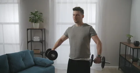 Athletic man is lifting dumbbells, training at home, fitness and healthy Stock Footage 147934084