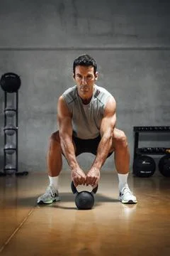 Athletic man lifting weight with kettle bell in gym. Stock Photos