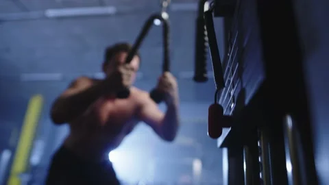 An athletic man lifts weights on an exercise machine in the gym. Stock Footage 239270699