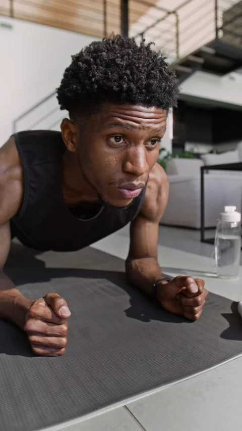 Athletic Man Lowering onto His Forearms and Staying in Plank Pose on Sports Mat Stock Footage 324153348