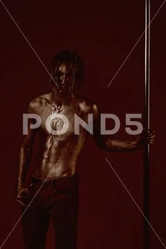 Athletic man make acrobatic elements on pylon. Pole dance sport. Strong dancer Stock Photos