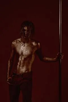 Athletic man make acrobatic elements on pylon. Pole dance sport. Strong dancer Stock Photos