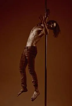 Athletic man make acrobatic elements on pylon. Muscular man with silver body art Stock Photos