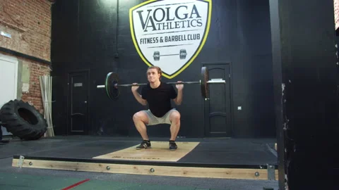 An athletic man is making a squat with a barbell Stock Footage 155256741