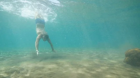 Athletic man in mask dives and swims underwater in ocean looking at wildlife. Stock Footage 112378384