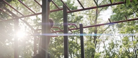 Athletic man moving across monkey bars on outdoor fitness playground Video stock 323934269