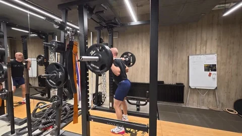 Athletic Man Performing Barbell Squat in Power Rack During Video stock 328809960