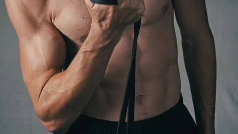 Athletic Man Performing Bicep Curls with an Elastic Band Stock Footage 315773835