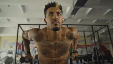 Athletic man performing dynamic dip exercise on parallel bars in a vibrant gym Video stock 318444707