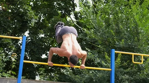 Athletic man performing dynamic workout routine on parallel bars, showcasing Stock-Footage 329756123