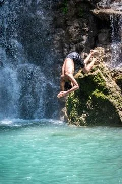 Athletic man performing a handstand dive into clear blue water near a water.. Fotos Stock