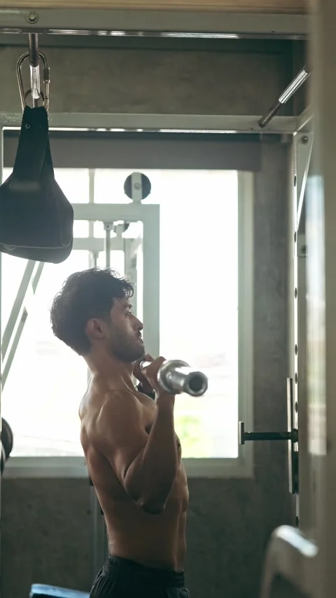 Athletic man performing an overhead barbell press in a gym, side profile by.. Stock Footage 347733611