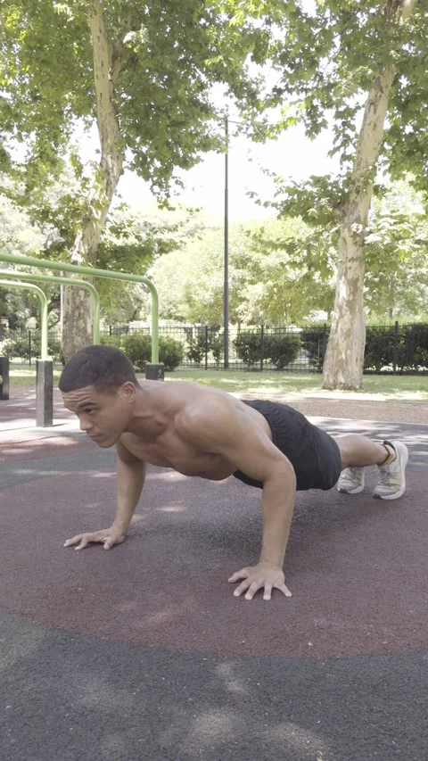 Athletic man performing push-ups on the ground in a calisthenics park. Video stock 326683586