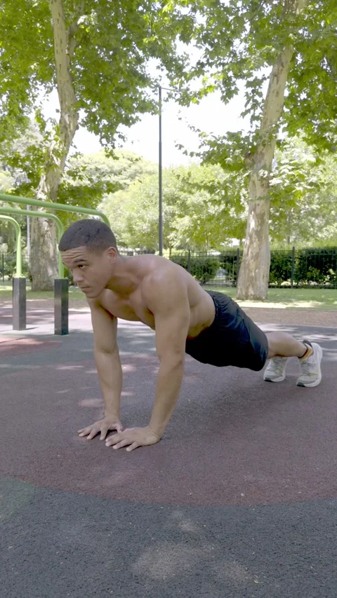 Athletic man performing push-ups at an outdoor calisthenics park. Video stock 326683621