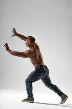 Athletic man posing in studio with dynamic movement showcasing strength and Stock Photos