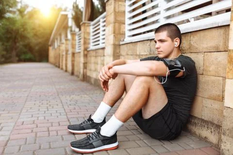 Athletic man posing on wall background, morning jog, exercise, rest after Jog Stock Photos
