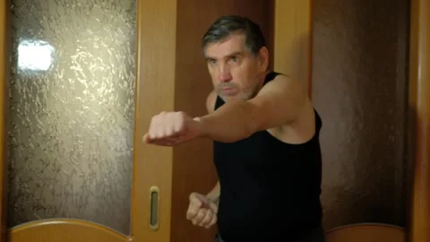 Athletic man practicing martial arts and boxing strikes at home Stock Footage 327868477