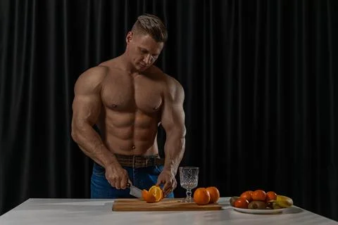 Athletic man preparing fresh oranges in a modern kitchen for a nutritious snack Stock Photos