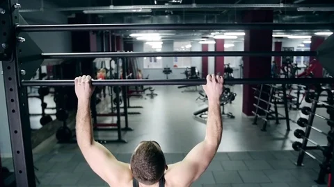 Athletic man pulling up on horizontal bar in fitness gym slow Stockbeeldmateriaal 74108035