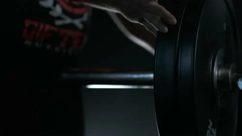 Athletic man putting on weight plates on a barbell bar Stock Footage 142279731