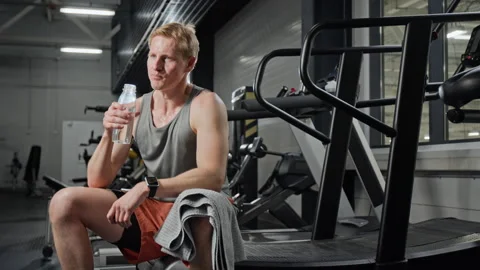 Athletic Man Resting on Treadmill and Drinking Water in Gym Stock Footage 339906393