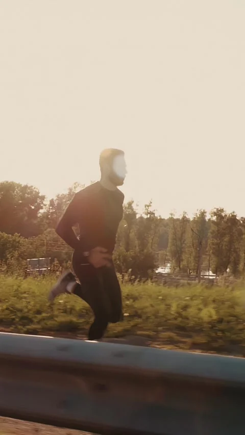 Athletic man running alongside a highway during sunset, showcasing determination Stock Footage 313259250