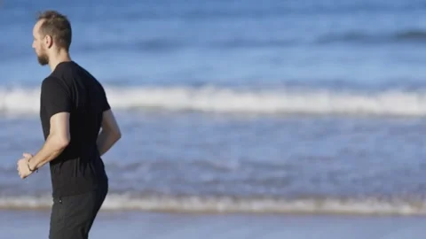 Athletic man running barefoot on the beach Stock Footage 320462534