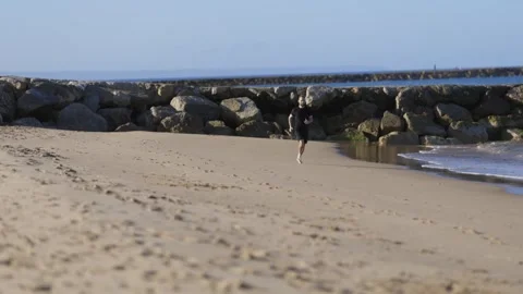 Athletic man running barefoot on a sandy beach Stock Footage 320462666