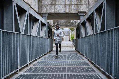 Athletic man is running on the bridge Stock Photos