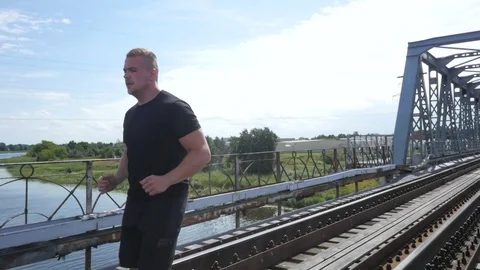 Athletic man running on the bridge, slow motion steadicam video Video stock 84004347
