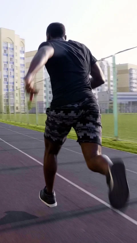 Athletic man running on track with modern buildings in the background showcasing Stock-Footage 313258588