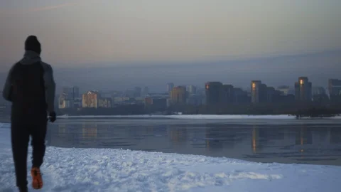 Athletic man running to winter river bank with cityscape view. Goal achievement Stock Footage 102322868