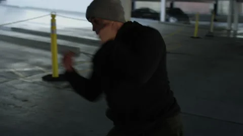 Athletic man shadowboxes in a city garage Video stock 153344328
